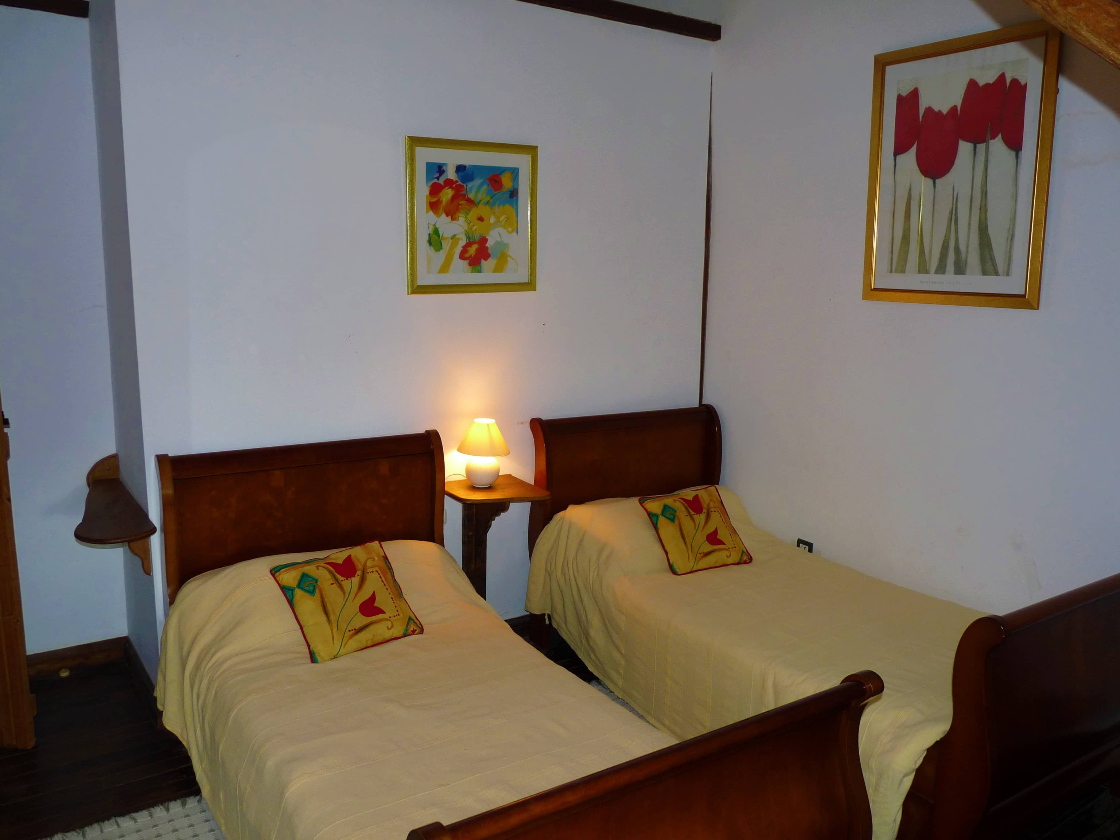 Spacious and comfortable bedroom of La Julerie cottage in Brittany, France, with a king-size bed, elegant rustic decor, a stone fireplace, and a panoramic view of the surrounding countryside. Perfect for a peaceful night's sleep after a day of sightseeing in the Brittany region.